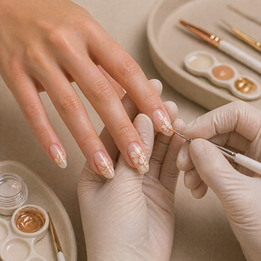 A nail artist hand-painting small white flowers on almond nails