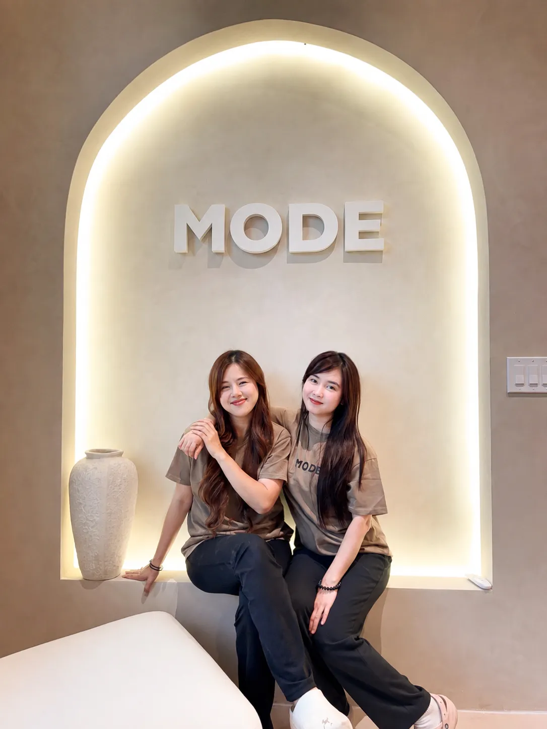 Mode's two co-owners, sitting in front of the lit MODE arch