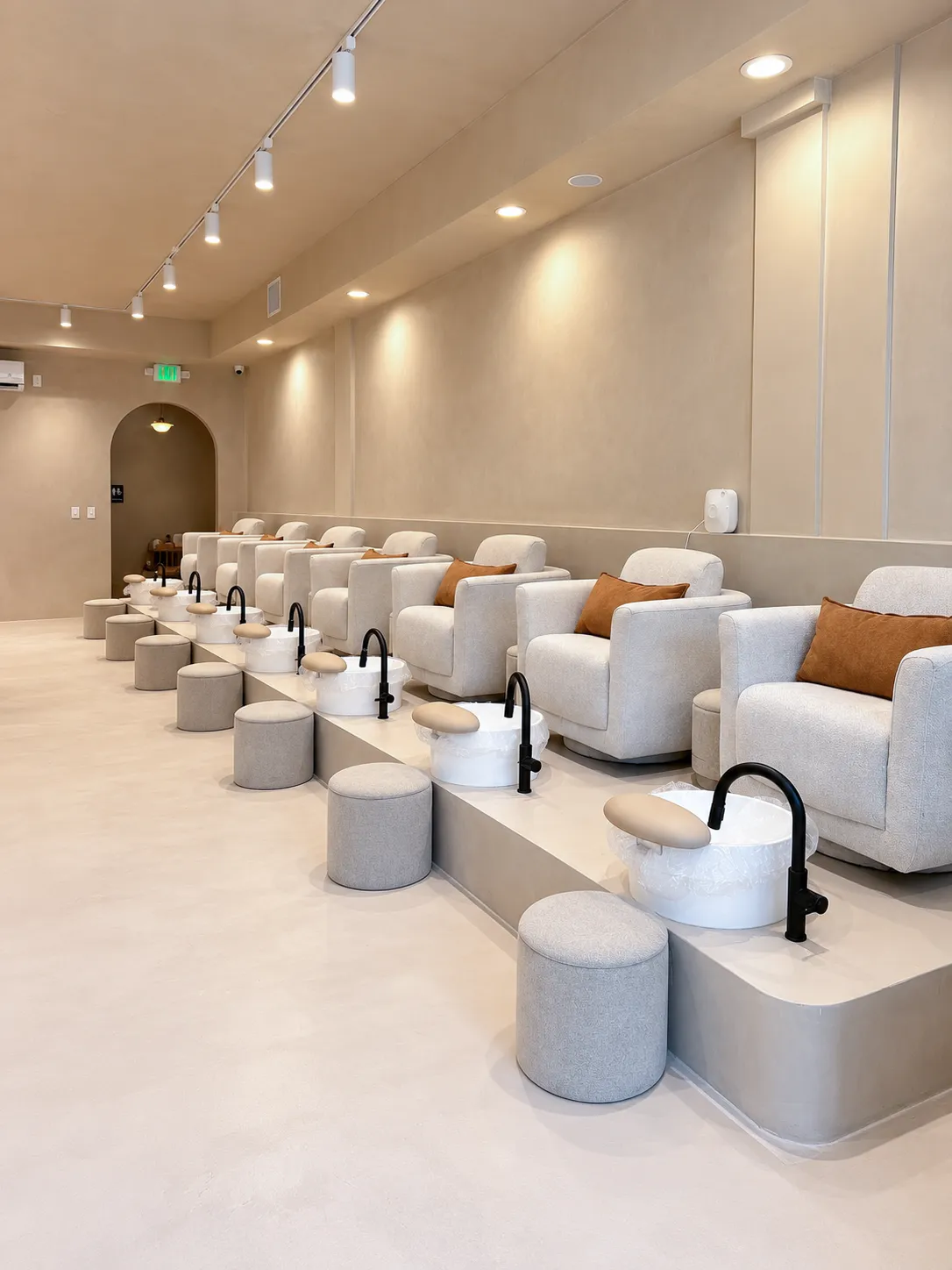 The pedicure lounge, a row of cream bouclé chairs
